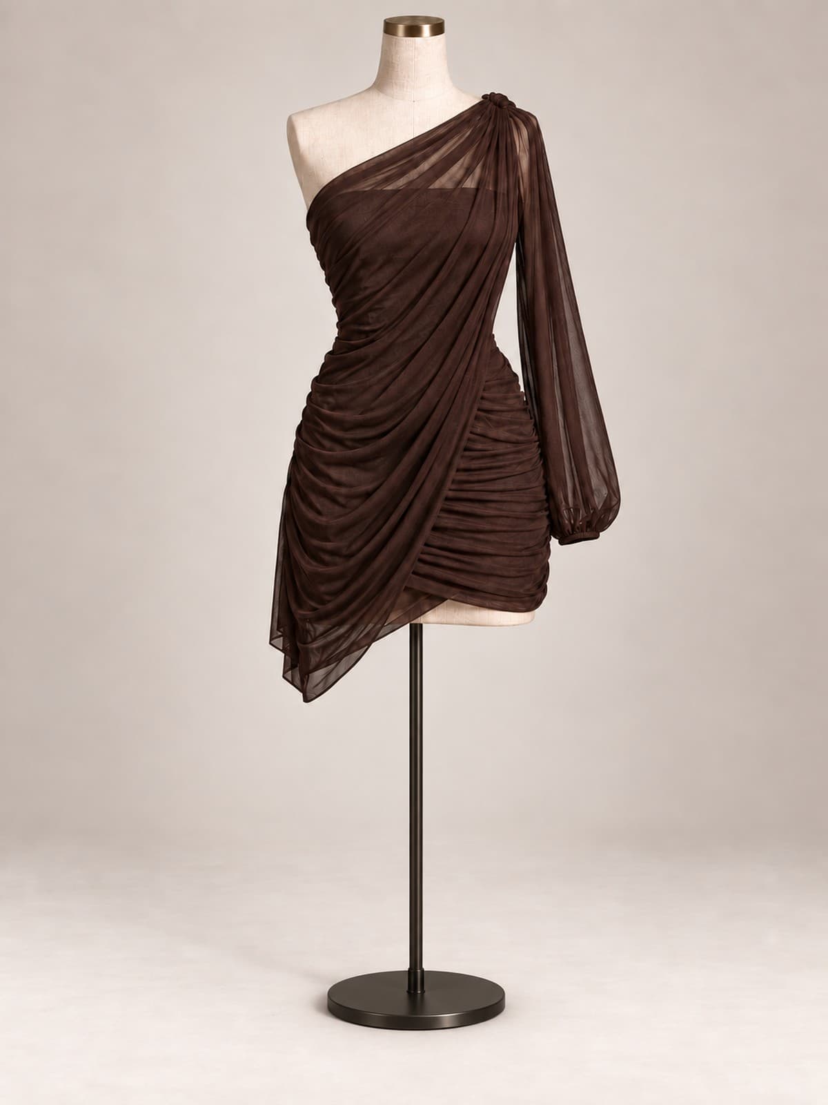 Vestido de festa Cacau: tule marrom franzido, decote de um ombro só com manga longa transparente e barra assimétrica curta, em manequim de ateliê.